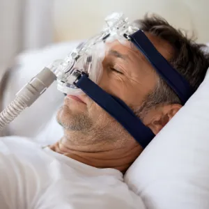 Adult man receiving sleep apnea therapy with a CPAP mask, related to sleep dentistry in Austintown